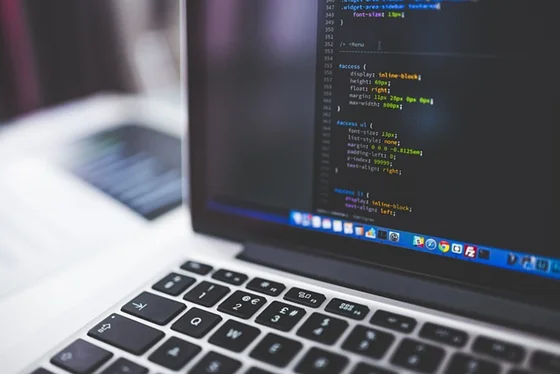 A clean desk setup with a laptop showing code